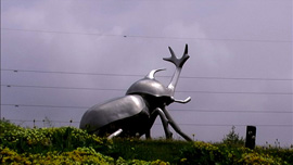 A giant silver kabuto mushi by the side of a highway