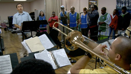 Javier Pena, music director, gives direction to the brass section as the choir sings in the background.