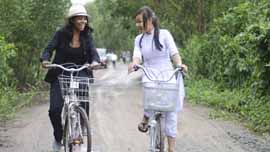 Gabrielle Union and local student Duyen Le ride bikes in Thu Thua, Vietnam.