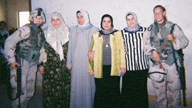 Specialist Shannon Morgan posing with Iraqi women in Ramadi, Iraq, 2004
