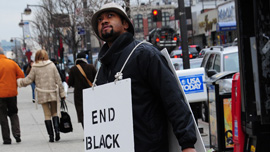 Director Shukree Tilghman wears a protest sign in Harlem
