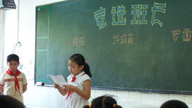 Xiaofei Xu, reads out her campaign promises whilst one of her election opponents, Cheng Cheng, looks on at  Wuhan Evergreen No. 1 Primary School.