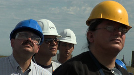 Native workers view the construction of a wind turbine