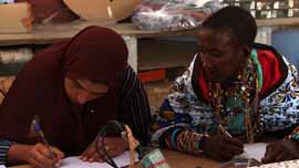 Rafea in the classroom at Barefoot College with a fellow student looking at what she's writing