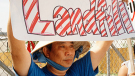 Community member holds up a “No Landfill” sign in front of Chef Menteur Landfill, 2006