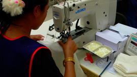 Worker sewing buttons onto a shirt at New Island Clothing factory, Phnom Penh, Cambodia, 2008 Worker sewing buttons onto a shirt at New Island Clothing factory, Phnom Penh, Cambodia, 2008