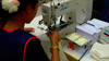 Worker sewing buttons onto a shirt at New Island Clothing factory, Phnom Penh, Cambodia, 2008