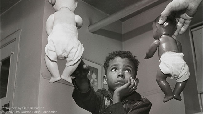 young boy choosing white doll