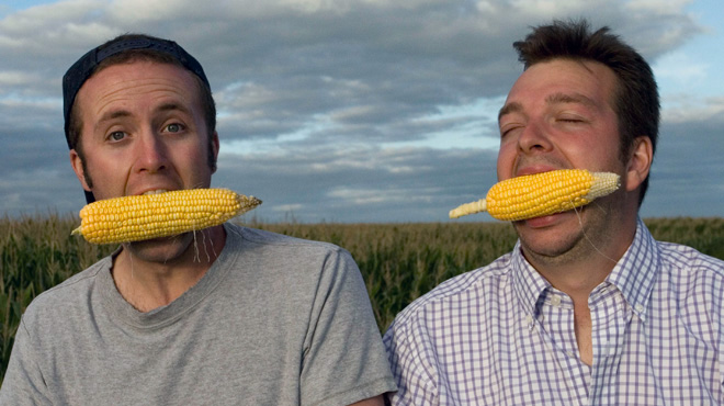 Ian Cheney and Curt Ellis with corn cobs in their mouth 